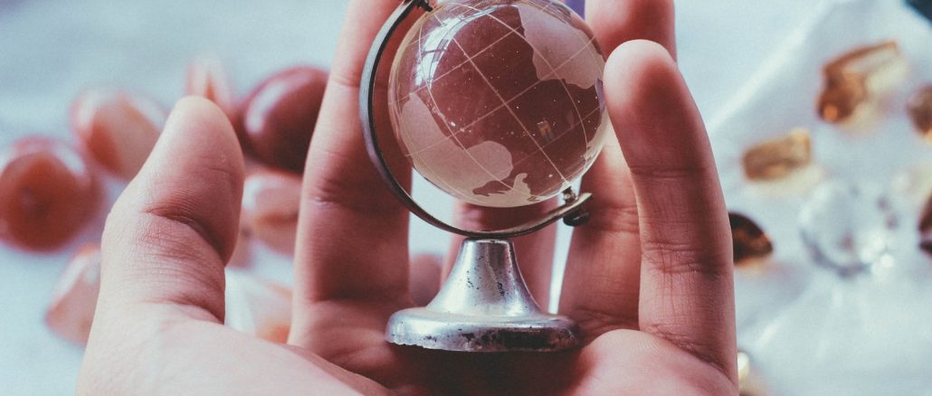 person holding gray metal framed desk globe paper weight